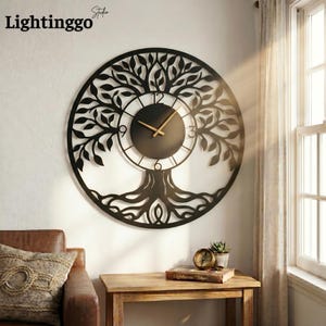 May include: A black metal wall clock with a tree of life design. The clock face is black with gold-colored hands and a circular frame. The clock is mounted on a white wall. The brand name "Lightinggo" is in the top left corner.