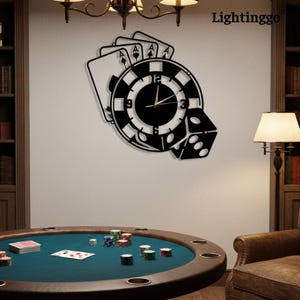 May include: Black metal wall clock featuring a poker chip design, playing cards, and a die. The clock hands are gold. The word "Lightinggo" is in the upper right corner. A poker table is in the foreground.