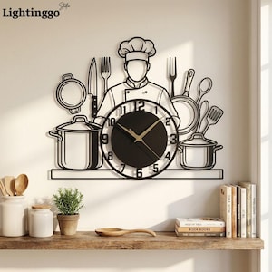 May include: A black metal wall clock featuring a chef silhouette surrounded by kitchen utensils including a knife, fork, pots, and pans. The clock face is circular with black numbers and gold hands, integrated into the centre of the design.