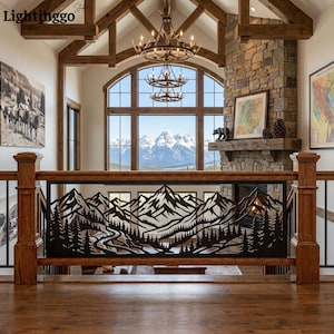 May include: A black metal railing insert featuring a laser-cut design of a mountain range with pine trees and a winding path. The panel is framed by a wooden railing structure in a room with a stone fireplace and a large window view.