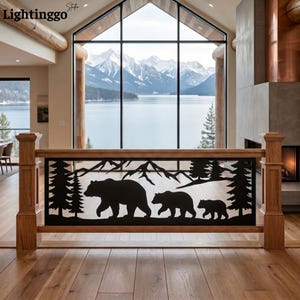 May include: A black metal railing insert featuring a laser-cut silhouette of a mountain range, pine trees, and a family of three bears walking in a line. The rectangular panel is framed by light-toned wooden posts and a matching wooden handrail.
