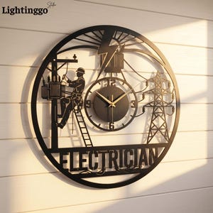 May include: A circular black metal wall clock featuring a silhouette of an electrician working on a utility pole, a high-voltage transmission tower, and a lightning bolt. The word ELECTRICIAN is cut out at the bottom with gold-colored clock hands.