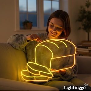 May include: A neon sign in the shape of a loaf of bread and a slice, glowing with a warm yellow light. The sign is held by a person wearing a gray sweater. The text "Lightinggo" is at the bottom right.