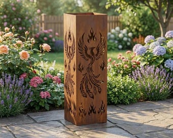 May include: A tall, rectangular, weathered metal garden sculpture with a phoenix design cut out on the sides. The sculpture is brown and stands on a stone patio, surrounded by flowers and greenery.