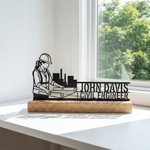 Può includere: Ornamento da scrivania in metallo nero per ingegnere civile. La silhouette raffigura una persona con elmetto e progetti, uno skyline e il nome "JOHN DAVIS CIVIL ENGINEER" su una base di legno.