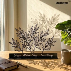 May include: A white ceramic mug with a black handle and the text "But First, Coffee" in a bold, black font. The mug is set against a blurred background, suggesting a cozy setting.