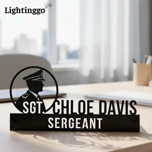 Pode incluir: Placa de mesa preta com a silhueta de uma pessoa em uniforme militar dentro de um círculo. A placa diz "SGT. CHLOE DAVIS SERGEANT" em letras brancas. O produto é feito de material preto e fica em uma mesa de madeira.