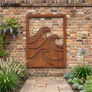 May include: A rectangular, rust-colored metal wall art piece featuring a wave design. The artwork is mounted on a brick wall and framed by a matching metal border. The image is set outdoors with greenery and a stone pathway.