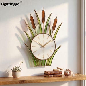 Puede incluir: Un reloj de pared decorativo con un diseño inspirado en la naturaleza. La esfera del reloj es blanca con manecillas y marcadores dorados. El reloj está rodeado de juncos y espigas de metal verde y marrón. La marca "Lightinggo" está en la esquina superior izquierda.