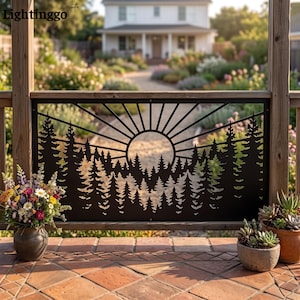 May include: A black metal decorative panel featuring a laser-cut design of a sun rising over a dense forest of pine trees. The rectangular panel is mounted within a wooden frame, displaying a silhouette of trees and sun rays against a background.