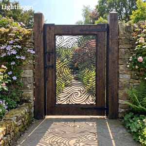 May include: A wooden garden gate featuring a central black metal panel with a decorative wave pattern. The gate is framed by two thick wooden posts and includes black metal hinges and a latch. The design casts a wave-shaped shadow on the stone path.
