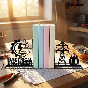 May include: A pair of black metal bookends featuring electrical engineering themes. One bookend displays a gear, circuit lines, a lightning bolt, and the text ELECTRICAL ENGINEER. The other shows a high-voltage transmission tower and transformer.