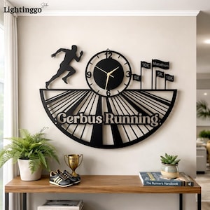Puede incluir: Reloj de pared de metal negro con una silueta de corredor, una esfera y el texto "Gerbus Running". Incluye banderas para distancias de 5K, 10K y Maratón. El reloj está montado en una pared beige.