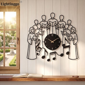 May include: A black metal wall clock featuring a stylized choir of nine figures holding songbooks, arranged in a semi-circle around a circular clock face with gold hands. Musical notes are integrated into the lower section of the design.
