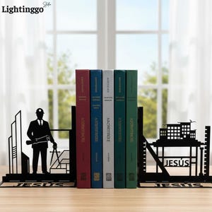 May include: A pair of black metal bookends featuring silhouettes of an architect with drafting tools and a building structure. The base of each bookend displays the word JESUS in cut-out lettering, supporting five books with colored spines.