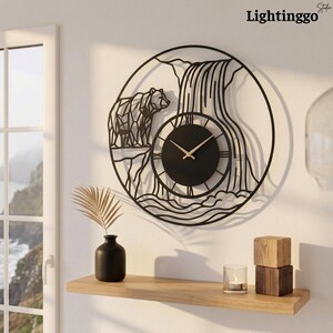 May include: A circular black metal wall clock featuring a geometric bear silhouette and a waterfall design. The clock face is solid black with thin gold-colored hands and no numerals. The brand name Lightinggo is printed in the top right corner.