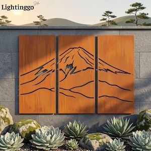 May include: A triptych wall art set featuring a laser-cut mountain landscape design on three rectangular, weathered orange-brown metal panels. The artwork displays a stylized mountain peak silhouette across the panels, creating a continuous scene.