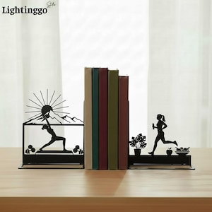 May include: Black metal bookends with a fitness theme. One bookend depicts a mountain scene with a person doing yoga. The other shows a person running with a water bottle and fruit. The word "Lightinggo" is in the top left corner.