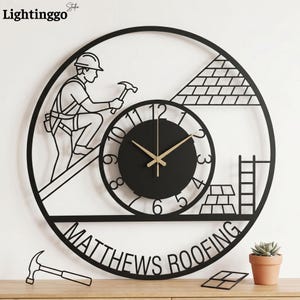 May include: Black metal wall clock featuring a construction worker silhouette, a clock face with gold hands, and the text "MATTHEWS ROOFING". The clock has a circular design with a hammer and other construction elements.