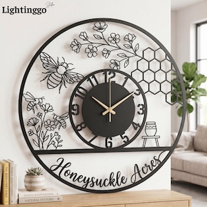 May include: Black metal wall clock with a circular design featuring bees, flowers, and a honeycomb pattern. The clock face is black with gold hands, and the words "Honeysuckle Acres" are written across the bottom.