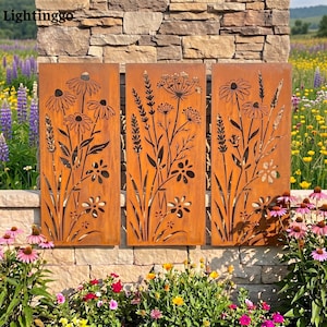 Puede incluir: Tres paneles metálicos rectangulares con acabado oxidado, cada uno con diseños de flores silvestres cortados con láser, incluyendo margaritas, lavanda y hierbas altas. Los paneles están dispuestos uno al lado del otro con siluetas botánicas.