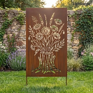 May include: A rectangular, rust-colored metal garden screen featuring a laser-cut design of a bouquet of wildflowers emerging from a tree stump. The panel has a weathered, oxidized finish and is supported by two thin metal stakes at the base.