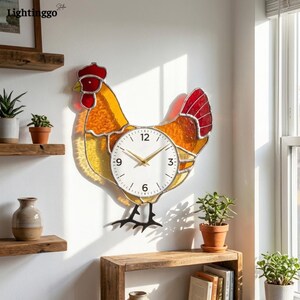 May include: A decorative wall clock shaped like a rooster. The clock face is white with black numbers and gold hands. The rooster's body is stained glass in shades of yellow, orange, and red. The clock is mounted on a white wall.