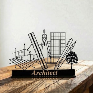 Puede incluir: Decoración de escritorio de arquitecto de metal negro con herramientas de arquitectura, un edificio y un árbol. La palabra "Architect" se muestra en la base. El diseño incluye una regla, un compás y un bolígrafo.
