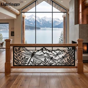 May include: A black metal railing insert featuring a laser-cut design of three dragonflies among foliage and mountain silhouettes. The rectangular panel is framed by natural wood posts and a top rail, showcasing intricate cutouts and clean lines.