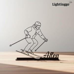 May include: Black metal ski-themed desk decor featuring a skier in action, complete with skis and poles. The skier is depicted in a dynamic pose, with the name "Allen" at the base. The Lightinggo Studio logo is in the upper right corner.