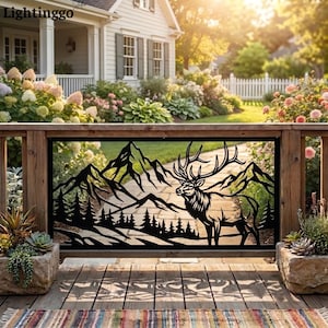 May include: A black metal decorative panel featuring a laser-cut silhouette of a majestic elk standing in front of a mountain range and a forest of pine trees. The rectangular panel is mounted within a wooden frame on a porch railing.