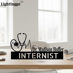May include: Black metal sign with a stethoscope, heartbeat line, and the name "Dr. Madison Hoffer, Internist." The sign is on a wooden surface, with the "Lightinggo Studio" logo in the top left corner.
