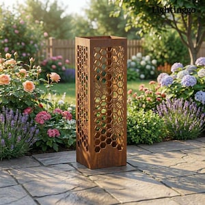 May include: A tall, rectangular, rusty brown metal garden lantern with a honeycomb and bee design. The lantern is placed on a stone patio, surrounded by colorful flowers and greenery. The word "Lightinggo" is visible in the top right corner.