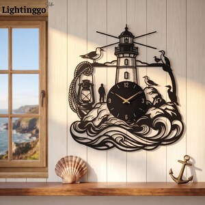 May include: A black metal wall clock featuring a lighthouse silhouette, a lantern, a person standing on rocks, and several birds. The clock face is circular with gold hands and numbers. The design includes stylized waves at the base of the structure.