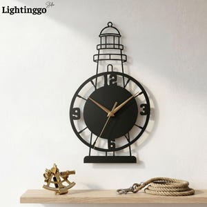 May include: A black metal wall clock shaped like a lighthouse with a circular face, gold-colored hands, and large numerals at the twelve, three, six, and nine o'clock positions. The clock features a cutout lighthouse silhouette design.