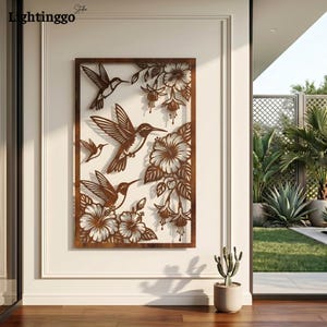 May include: A decorative metal wall art piece featuring hummingbirds and flowers. The artwork is a rectangular frame with cut-out designs of hummingbirds, hibiscus, and other floral elements. The metal has a brown, rustic finish.