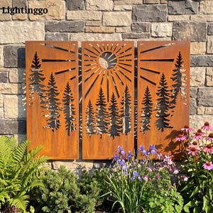 May include: A three-panel rust-colored metal wall art set featuring laser-cut silhouettes of pine trees and a sunburst design. The panels display a weathered, oxidized finish with intricate cutouts depicting a forest landscape under a sun.