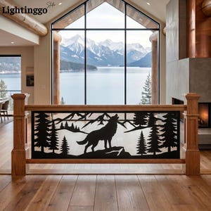 May include: A black metal railing insert featuring a laser-cut silhouette of a howling wolf standing on a rocky outcrop, surrounded by pine trees and mountain peaks. The rectangular panel is framed by natural light-toned wooden posts and rails.