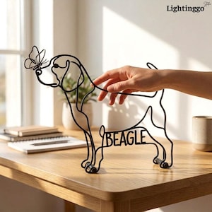 May include: A black wire sculpture shaped like a beagle dog with a butterfly perched on its nose. The word BEAGLE is integrated into the lower body of the wire frame. The sculpture is made of thin metal wire and stands on a flat surface.