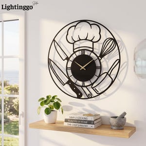Peut inclure: Une horloge murale circulaire en métal noir représentant une toque de chef, deux couteaux, un fouet et une casserole. Le cadran comporte des chiffres romains et des aiguilles dorées. Le design ajouré projette une ombre sur le mur.