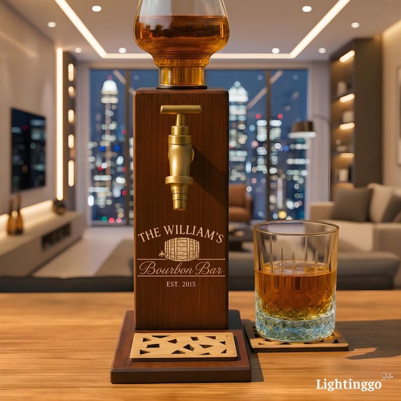 Op de afbeelding: Een houten bourbon dispenser met een messing kraan en een glazen karaf. De dispenser is gegraveerd met "The William's Bourbon Bar" en "EST. 2015". Een glas bourbon staat op een houten onderzetter.
