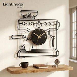 Puede incluir: Un reloj de pared de metal negro con forma de máquina de café espresso, con una esfera circular, manecillas doradas y los números 3, 6, 9 y 12. El diseño incluye una tolva de granos, un portafiltros y una taza. El texto Lightinggo Studio es visible.