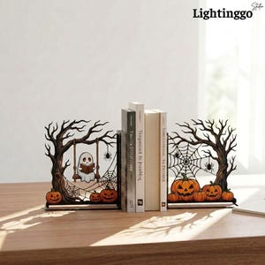 May include: A pair of Halloween-themed bookends featuring dark, gnarled trees. One side shows a white ghost reading a book on a swing with a spiderweb, and the other side displays orange jack-o'-lanterns and a large spiderweb between the branches.