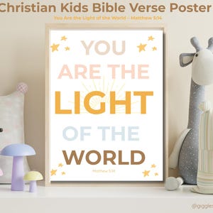 May include: A framed poster with the text "YOU ARE THE LIGHT OF THE WORLD" in various colors. The poster includes the Bible verse Matthew 5:14 and is decorated with star shapes. The image is part of a children's room decor.