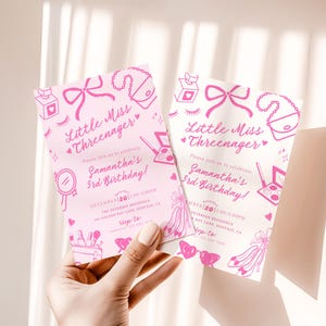 May include: Two pink birthday party invitations with the text "Little Miss Threenager" and "Samantha's 3rd Birthday!" are held in a hand. The invitations feature illustrations of makeup, bows, and purses.