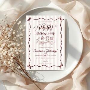 A soft and elegant Pilates birthday invitation featuring hand-drawn Pilates reformer illustrations, Pilates accessories, and minimal line art in a neutral beige and deep red color palette. This editable Pilates birthday party invitation template is designed with subtle stripes, a whimsical border, and modern script typography, perfect for a Pilates-themed birthday celebration or fitness party.