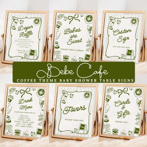 May include: A collection of six gold-framed signs with a coffee theme for a baby shower. The signs feature green text and illustrations, including phrases like "Diaper Raffle," "Babies are Sweet," and "Cards & Gifts." The signs are arranged on a white background.