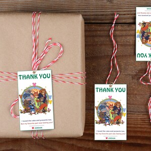 Puede incluir: Un regalo envuelto con una etiqueta de "Gracias" y cordel rojo y blanco. La etiqueta presenta una ilustraci&oacute;n de dibujos animados de animales y el texto "Gracias". El regalo est&aacute; envuelto en papel marr&oacute;n.