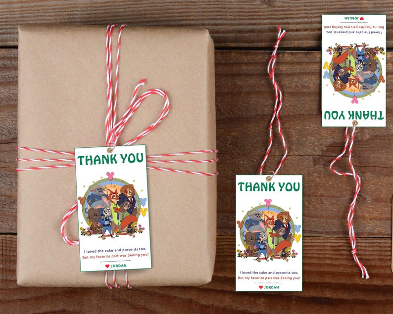 Puede incluir: Un regalo envuelto con una etiqueta de "Gracias" y cordel rojo y blanco. La etiqueta presenta una ilustraci&oacute;n de dibujos animados de animales y el texto "Gracias". El regalo est&aacute; envuelto en papel marr&oacute;n.