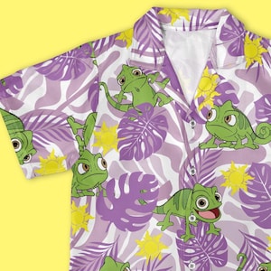 May include: Short-sleeved button-down shirt with a purple and white tropical leaf pattern. The shirt features green chameleon cartoon characters and yellow flower accents. The shirt has a classic collar and a relaxed fit.